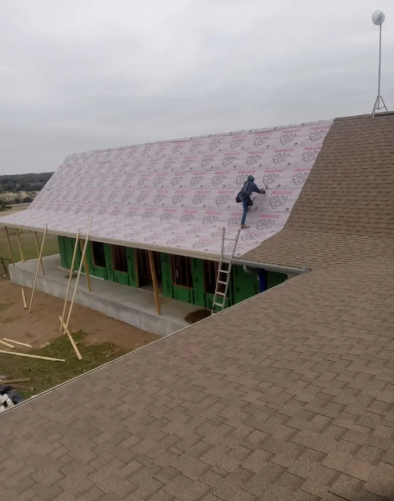 Worker preparing underlayment for a metal roof installation in Monahans
